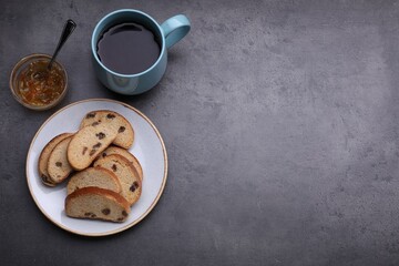 Sweet hard chuck crackers with raisins, jam and cup of tea on grey table, flat lay. Space for text