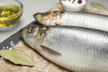 Slate plate with salted herrings, oil and spices on grey table, closeup