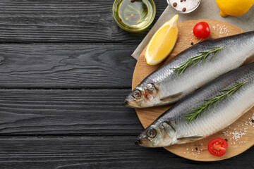 Delicious salted herrings and ingredients on black wooden table, flat lay. Space for text