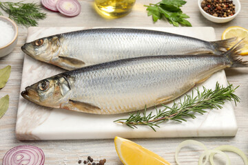 Delicious salted herrings and different ingredients on wooden table