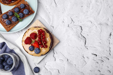 Crunchy rice cakes and rye crispbreads with different toppings on white textured table, flat lay. Space for text