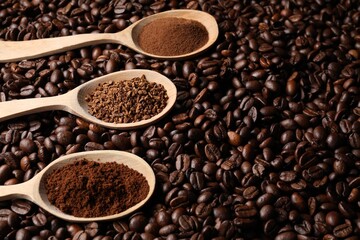Fototapeta premium Spoons with different types of coffee on roasted beans. Space for text