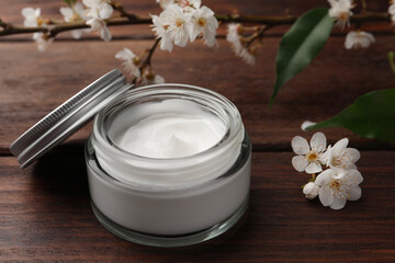 Fototapeta na wymiar Jar of face cream and flowers on wooden table