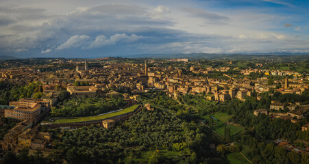 Fototapeta premium Scenery of Siena, a beautiful medieval town in Tuscany, view of the Dome and Bell Tower of Siena Cathedral, landmark Mangia Tower and Basilica of San Domenico,Italy. Aerial drone shot, october 2022