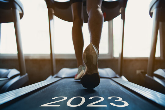 Happy new year 2023,2023 symbolizes the start of the new year. Close up of feet, sportman runner running on treadmill in fitness club. Cardio workout. Healthy lifestyle, guy training in gym.