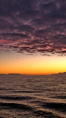 Popcorn clouds illuminated pink over the silhouette of a mountain, at sunset at Cierva Cove, Antarctica