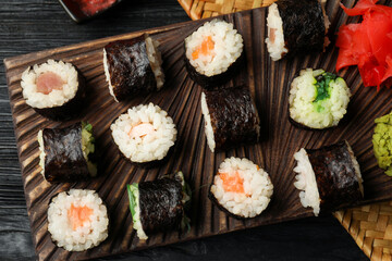 Tasty sushi rolls served on black wooden table, flat lay