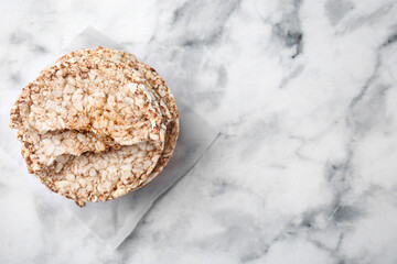 Stack of crunchy buckwheat cakes on white marble table, top view. Space for text
