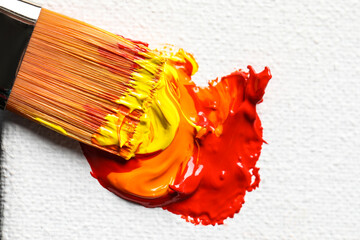 Beautiful colorful oil paints and brush on white canvas, top view