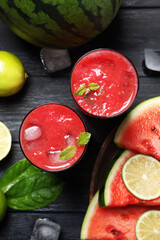 Glasses of delicious fresh watermelon juice, lime, mint and ice on black wooden table, flat lay
