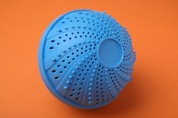 Dryer ball for washing machine on orange background. Laundry detergent substitute