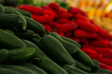 Heap of fresh green Serrano peppers on counter at market, closeup. Space for text
