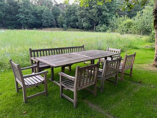 Obraz premium Wooden table with bench and chairs in garden. Landscape design