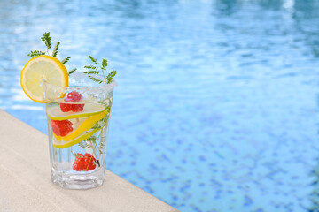 Delicious refreshing lemonade with raspberries near swimming pool, space for text