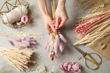 Florist making bouquet of dried flowers at grey stone table, top view