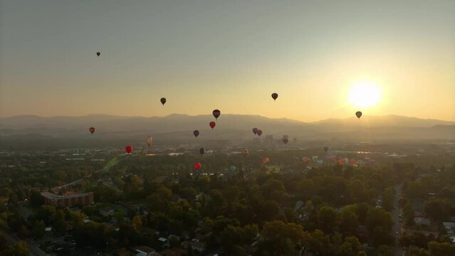 Wide aerial shot of hot air balloons floating through a hazy valley in America.