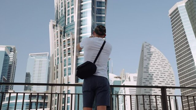 Medium Shot Of A Man Taking A Video Of A Skyscraper Hotel