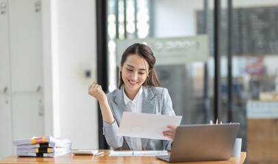 Happy excited successful business asian woman triumphing in office