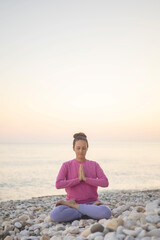 Fototapeta na wymiar Smiling woman yoga meditation siddhasana lotus namaste hands sea sunset beach sky horizon landscape