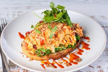 A serving of Chilli Scramble, scrambled eggs with sweet chilli sauce and a piece of toasted sourdough bread