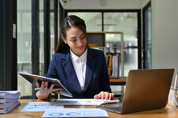 Fototapeta premium Asian businesswoman concentrating on her financial and sales report, working at her desk