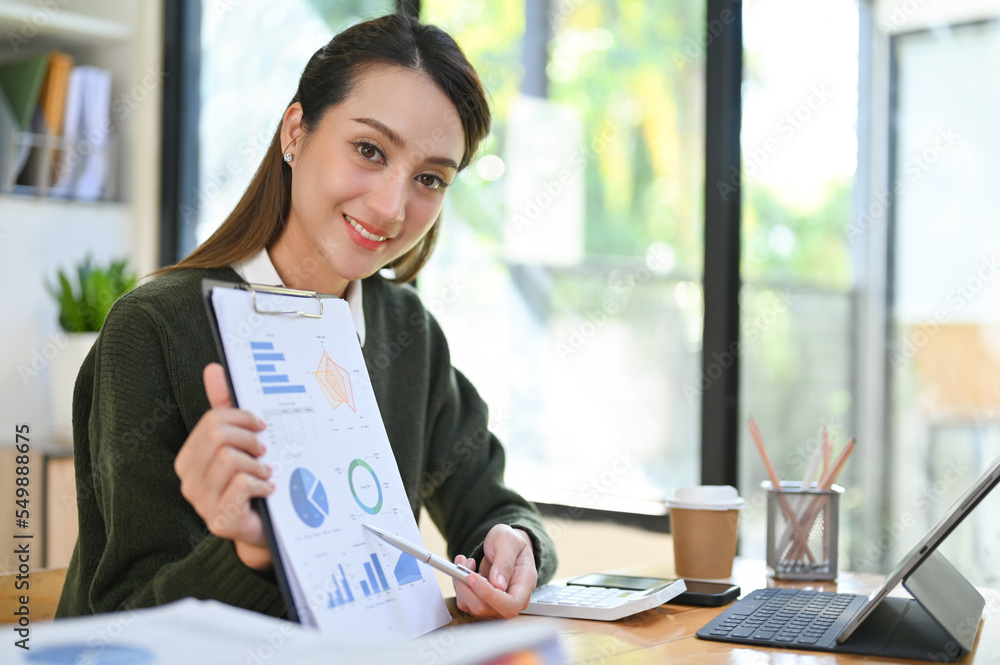 Wall mural beautiful asian businesswoman working with a financial report paperwork, sitting at her desk.