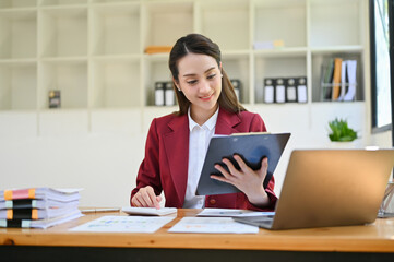 Professional Asian businesswoman reading an information on a document, working at her desk