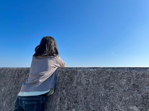 堤防から空を見上げる小学生の女の子