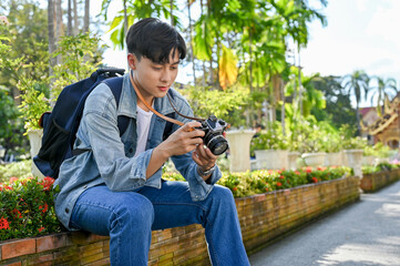 Handsome Asian male traveler preparing his camera before shooting, traveling at beautiful temple.