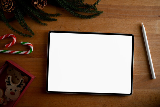 Workspace in Christmas theme decor with tablet white screen mockup on wood background.