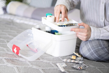 Female housewife checking medicines at domestic first aid kit neatly placing storage organization