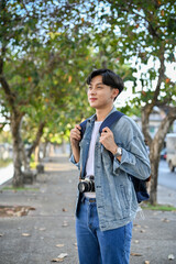 Handsome Asian male traveler or backpacker with his backpack strolling around the city.