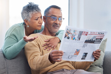 Senior couple, shocked and surprised by news while reading newspaper on sofa in living room at home...