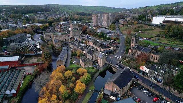 Aerial footage of the market town centre of Sowerby Bridge. UK town with river and canal set in a valley known as Calderdale, Kirklees. Streets and shops and busy traffic