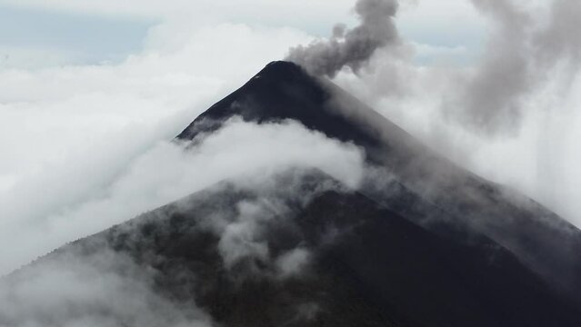 Drone video of an active volcano half covered by clouds in Antigua, Guatemala