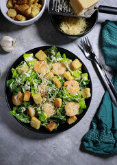 Cesar salad with grilled shrimp, croutons and parmesan cheese on grey marble table 