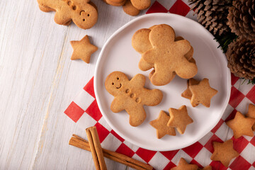 Homemade gingerbread men cookies on rustic white wooden table, traditionally made at Christmas and the holidays. Table top view.