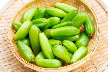 Bilimbi fruit in bamboo basket on white background.