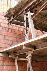 Reinforced scaffolding for the work of masons in the construction of brick walls. Apparel for work on the construction site and storage of materials. Close-up. Construction of brick walls.