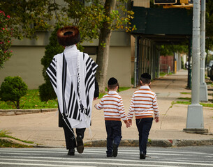 a hasidic jewish man walking down the street in williamsburg brooklyn with his sons