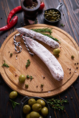 Spanish fuet salami sausageon wooden cutting board at domestic kitchen