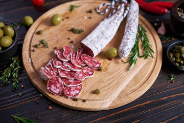 Spanish fuet salami sausageon wooden cutting board at domestic kitchen