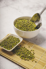 fresh mung beans in ceramic dishes against a white stone background, coppy space.