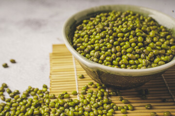 fresh mung beans in ceramic dishes against a white stone background, coppy space.