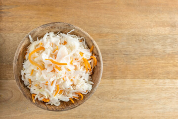 Sauerkraut in wooden bowl over rustic background.