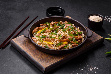 Tasty dish of Asian cuisine with rice noodles, chicken, asparagus, pepper, sesame seeds and soy sauce