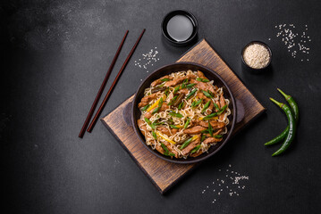 Tasty dish of Asian cuisine with rice noodles, chicken, asparagus, pepper, sesame seeds and soy sauce