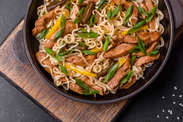 Tasty dish of Asian cuisine with rice noodles, chicken, asparagus, pepper, sesame seeds and soy sauce