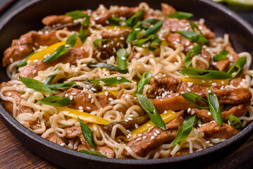 Tasty dish of Asian cuisine with rice noodles, chicken, asparagus, pepper, sesame seeds and soy sauce