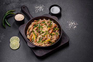 Tasty dish of Asian cuisine with rice noodles, chicken, asparagus, pepper, sesame seeds and soy sauce